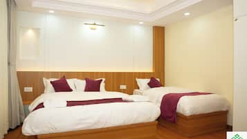 Ein Hotelzimmer mit zwei Betten, Holz Kopfteilen, weißer Bettwäsche und einer Deckenleuchte.