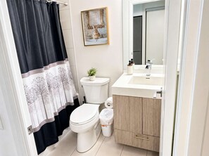 A bathroom with a toilet, sink, cabinet, and a framed picture on the wall.
