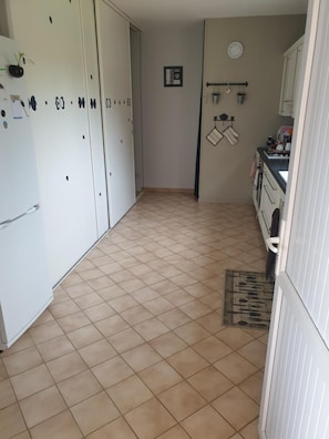 Eine Küche mit weißen Schränken, einem gefliesten Boden und einer Uhr an der Wand.