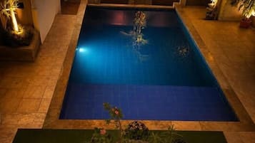 Una piscina rodeada de plantas y una mesa con un centro de mesa decorativo.