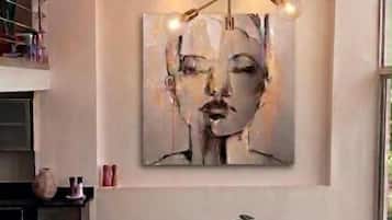 Un comedor con una lámpara de araña moderna, un cuadro abstracto grande y una mesa de comedor negra con cuatro sillas.