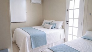 A bedroom with two beds, a window, and an air conditioning unit.