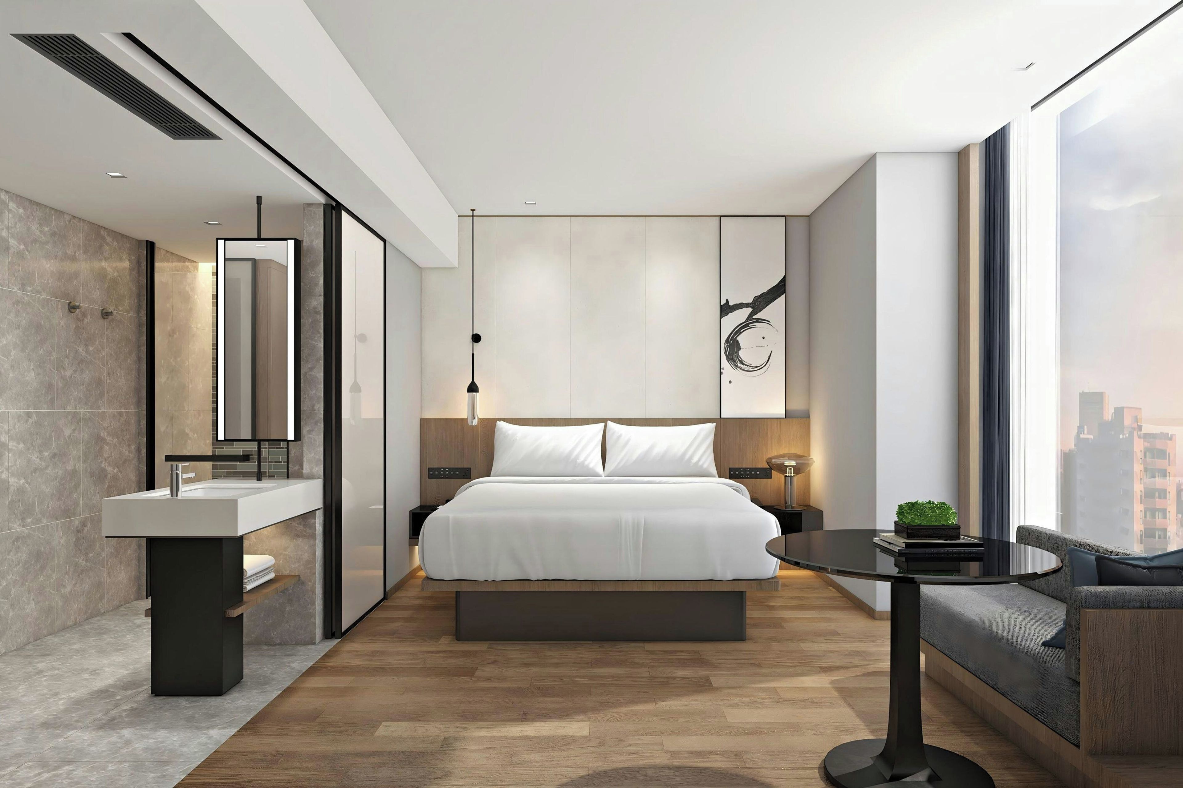 Una habitación de hotel moderna con una cama grande, una mesita de noche, una pequeña mesa redonda, un sofá y vistas a la ciudad.