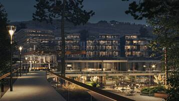 Un hôtel moderne à plusieurs étages, doté d’une terrasse et d’un magasin « GUCCI » bien visible.
