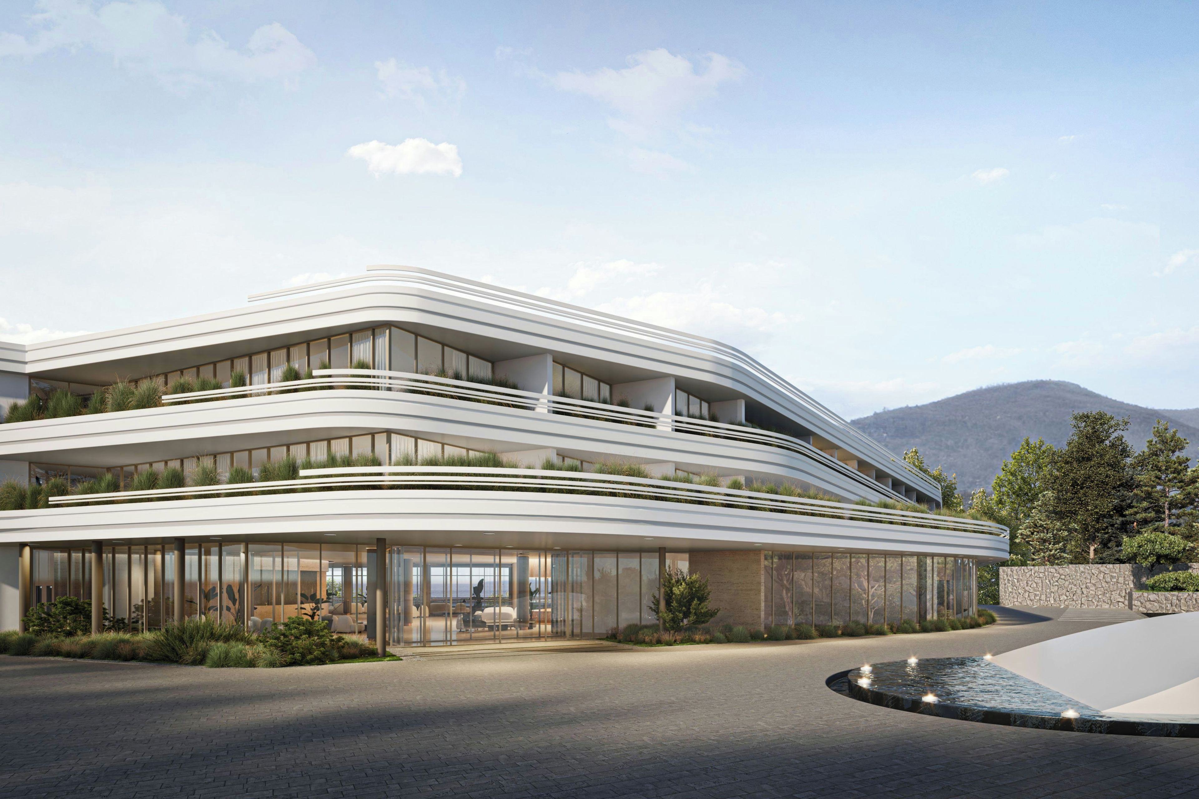 Un bâtiment moderne à la façade incurvée, doté de grandes fenêtres et d’un espace d’entrée aménagé.