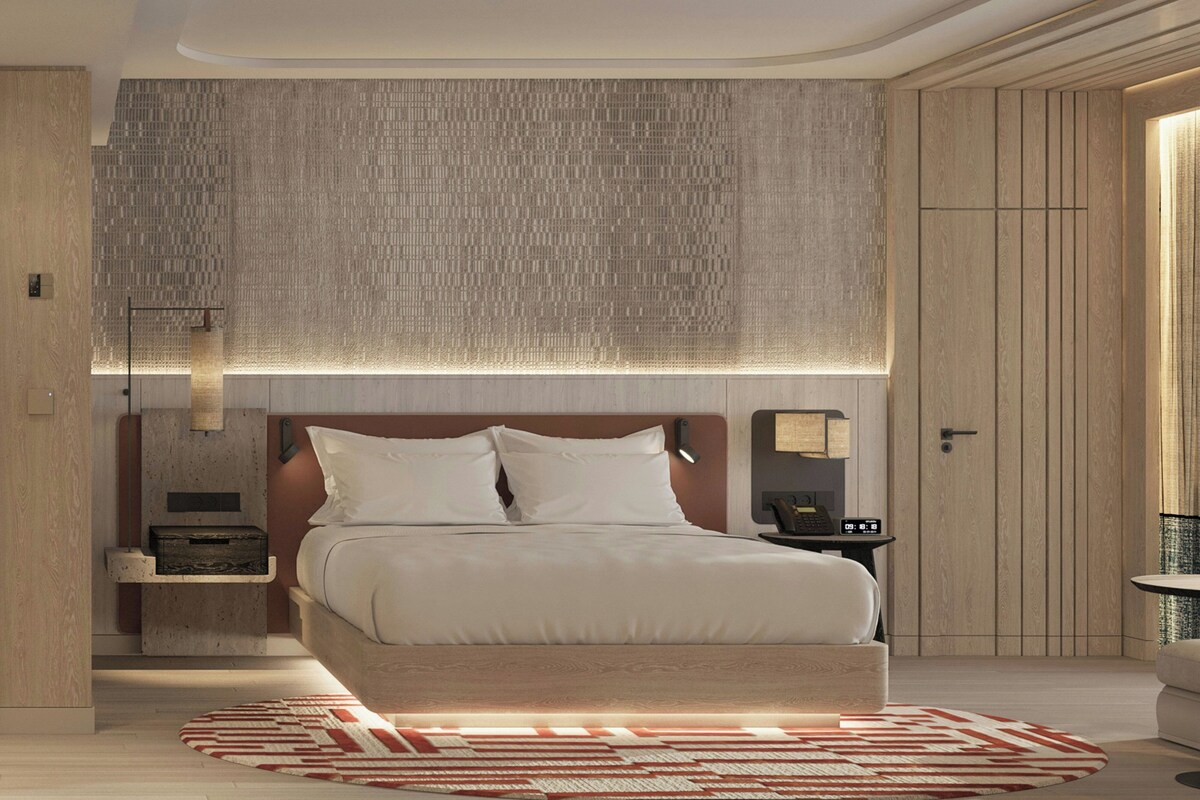 A modern bedroom with a large bed, a nightstand, a wall-mounted lamp, and a wooden wardrobe.