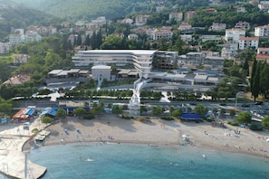 A coastal area with a modern building complex, a beach, and residential buildings in the background. - Opatija Marriott Resort & Spa (Opatija)