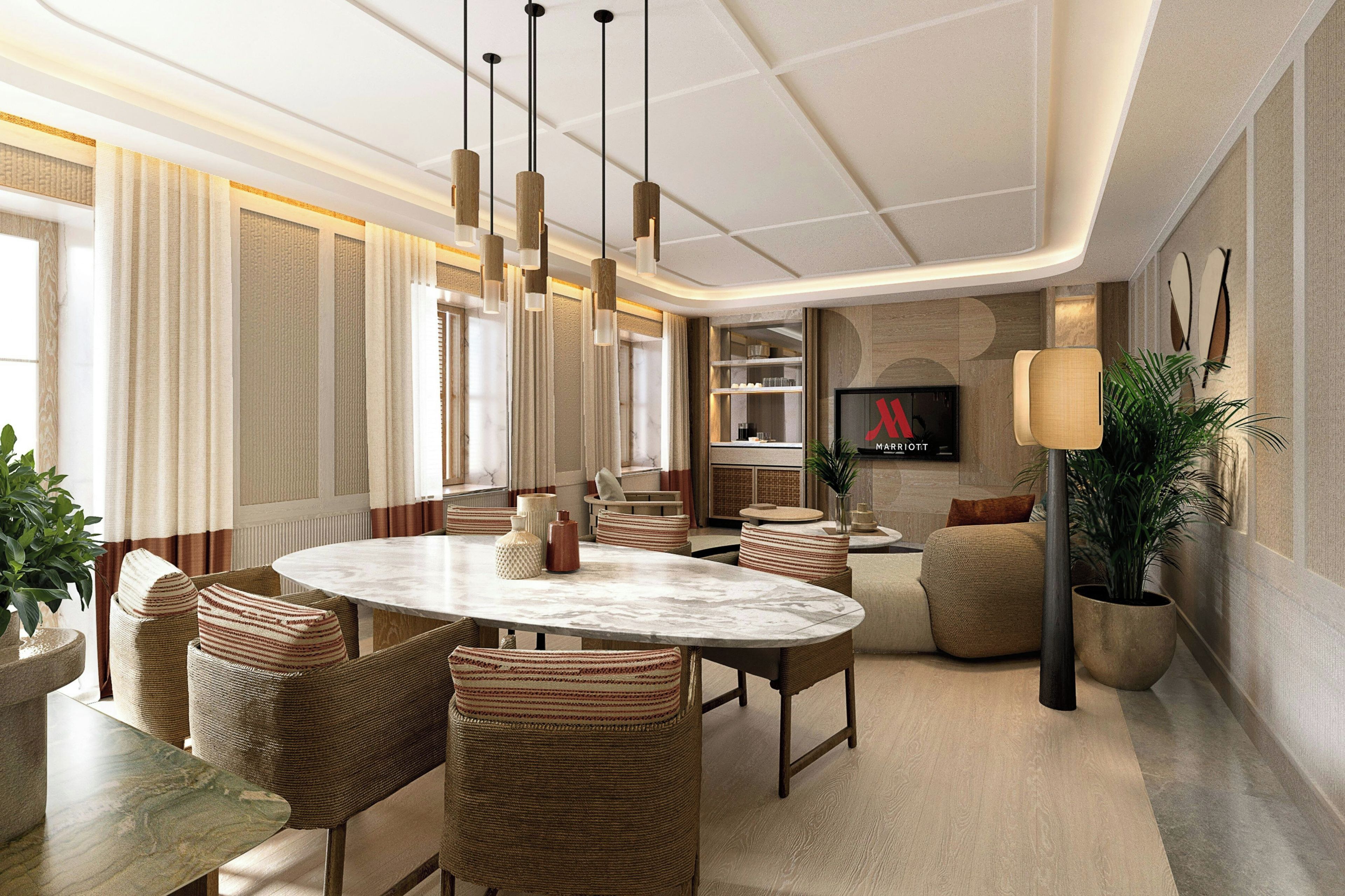 Un espace repas moderne avec une table ronde, des chaises en osier, des luminaires suspendus et un téléviseur fixé au mur.