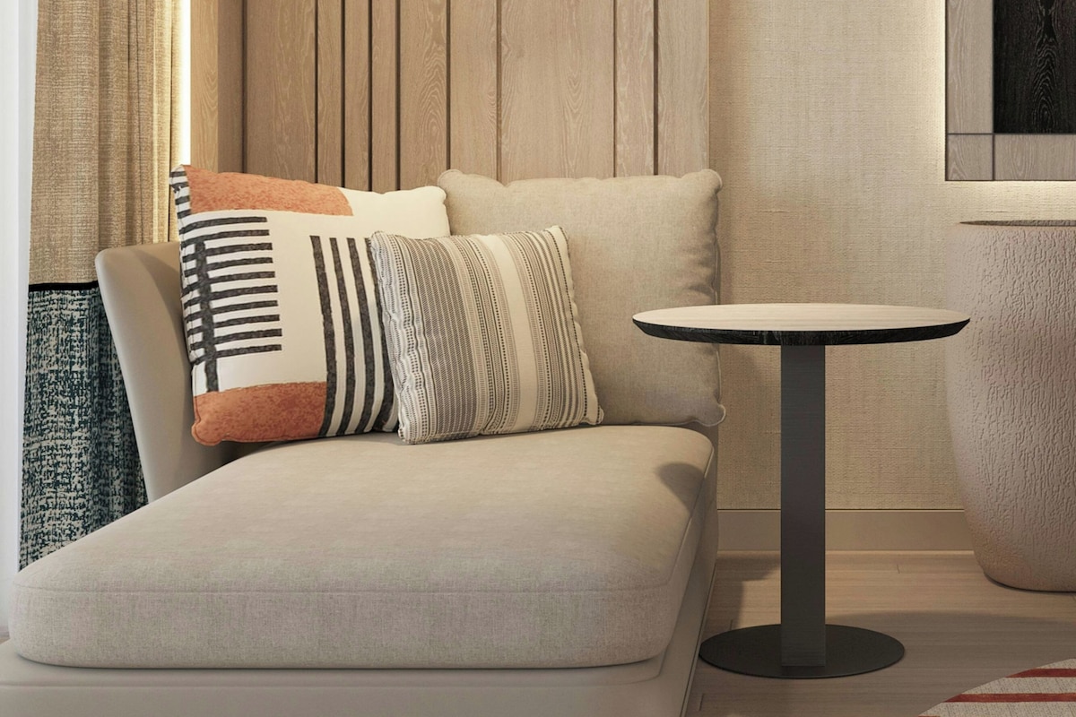 A modern living room with a sofa, a round table, and a hanging light fixture.