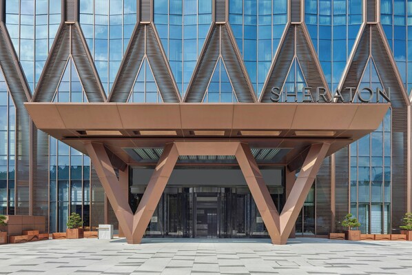 A modern building with a distinctive geometric entrance structure and reflective glass facade.