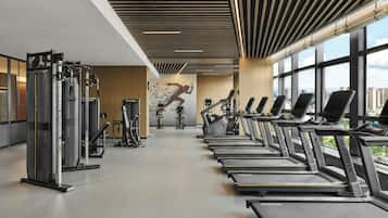 A gym with treadmills, weight machines, and a large window with a city view.