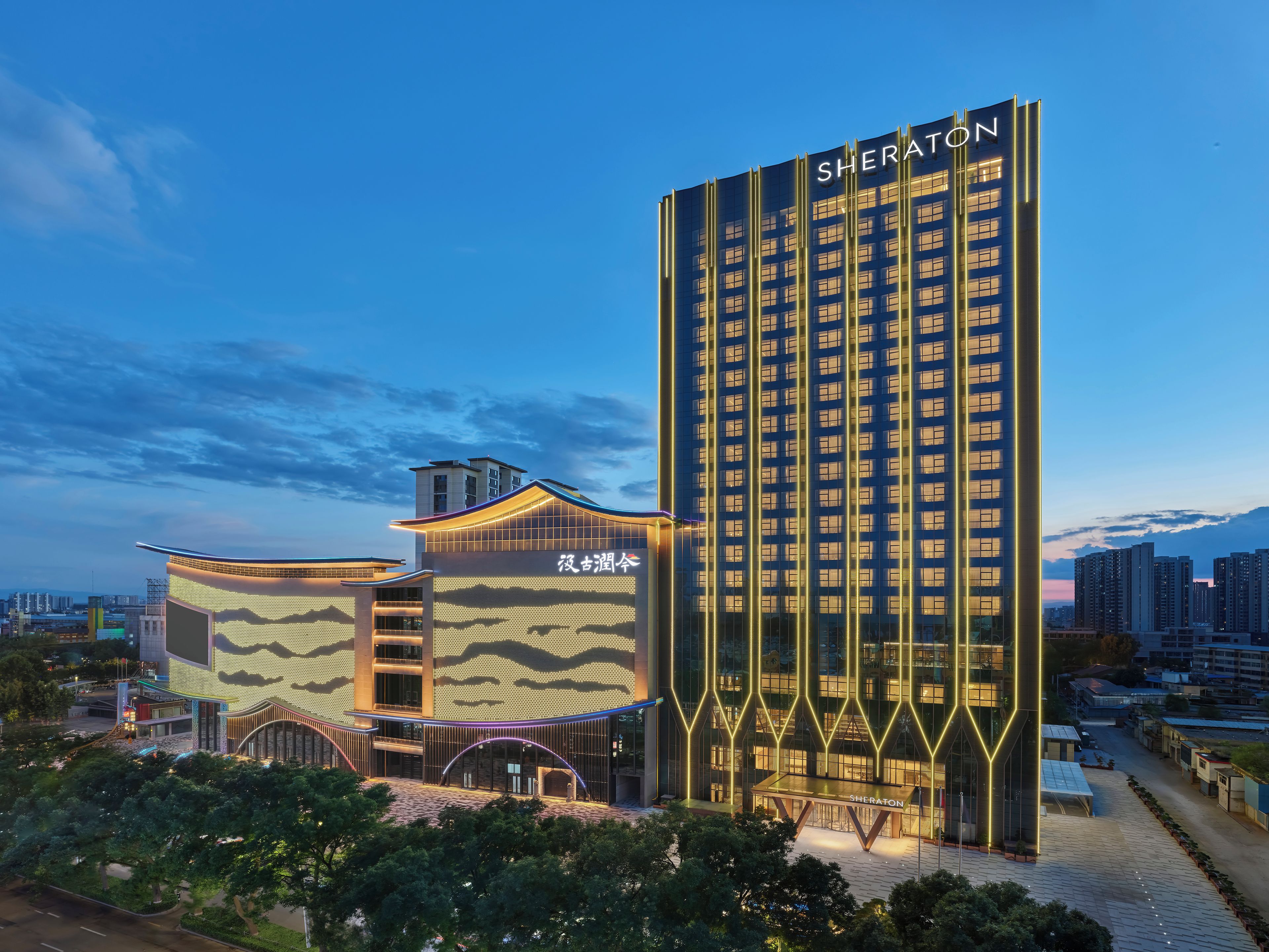 Un hotel Sheraton con un diseño moderno, que presenta una estructura vertical destacada y un edificio curvo con una fachada ondulada.