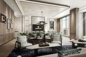 A modern dining area with a central table, surrounded by chairs, and a large screen displaying the Sheraton logo.