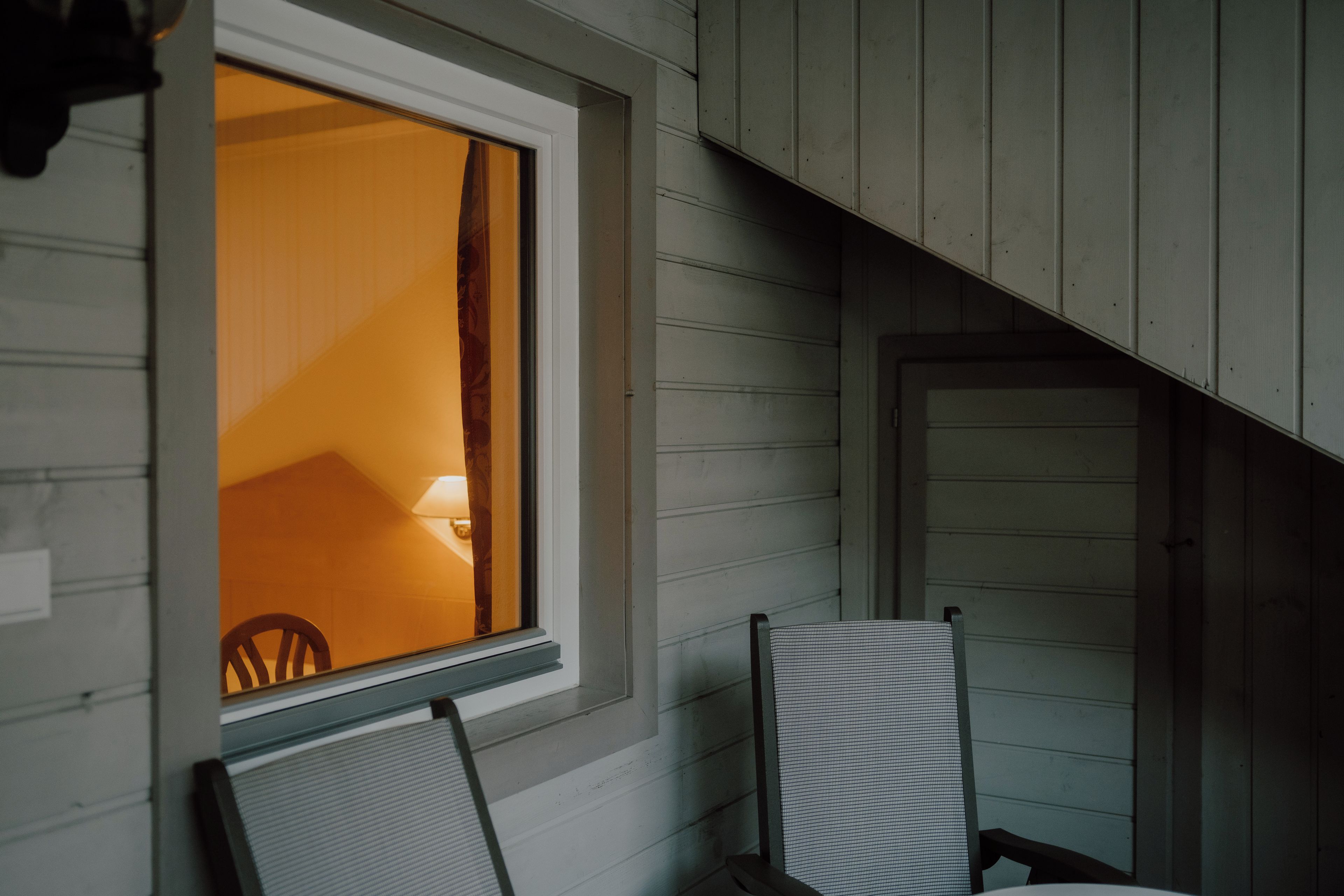 Ein Zimmer mit Fenster, Stuhl und Tür.