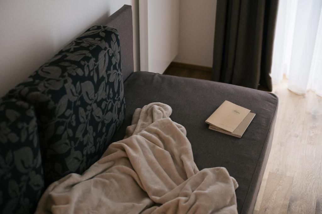Ein Sofa mit einem gemusterten Kissen, einer beigen Decke und einem Buch darauf.