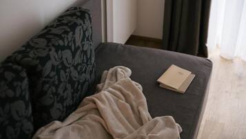 Ein Sofa mit einem gemusterten Kissen, einer beigen Decke und einem Buch darauf.
