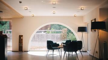 A modern interior with a large arched window, a dining area with chairs, and a floor lamp.