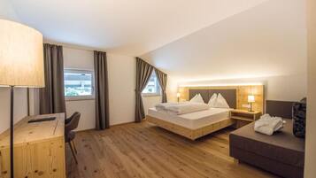A hotel room with a bed, a desk, a chair, a sofa, and a window with curtains.