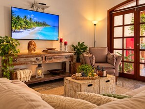 Una sala de estar con televisor, sofá, mesa de centro y lámpara.