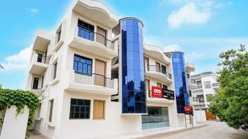 A multi-story hotel with balconies, a central glass elevator, and a sign for 'OYO Townhouse Hotel'.