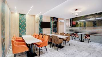 A conference room with a long table and chairs, a flat-screen TV, and an air conditioning unit.