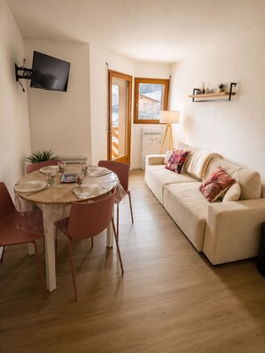 A compact living space with a dining area, a sofa, and a TV mounted on the wall. - Mountain views in the heart of the slopes, with a balcony, Wi-Fi, and a parking space. (Métabief)