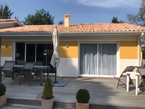 A modern house with a tiled roof, a covered patio with outdoor furniture, and a sliding glass door. - Bed and Breakfast 'Le Pas Des Chevreuils' with Wi-Fi (Salles)