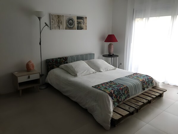 A bedroom with a bed, a nightstand, a lamp, a vase, and a wall art piece. - Bed and Breakfast 'Le Pas Des Chevreuils' with Wi-Fi (Salles)