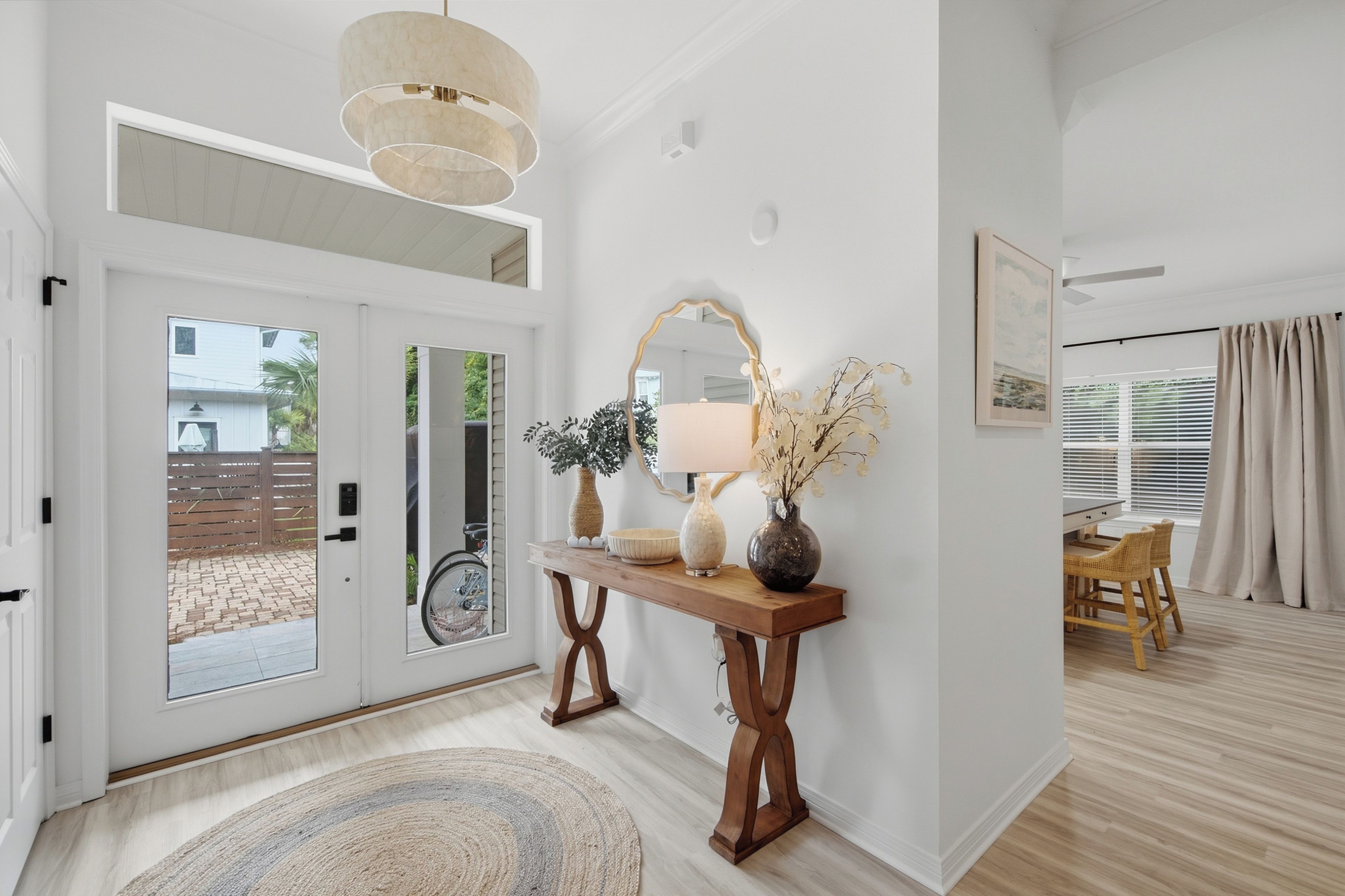 A modern interior with a wooden console table, a mirror, and a door leading to an outdoor area.