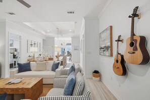 Ein modernes Wohnzimmer mit einer Couch, einem Couchtisch und zwei an der Wand befestigten Gitarren.