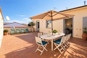 A patio with a table and chairs, a large umbrella, and a view of the surrounding area. - Frontemura House with a Terrace (Lucca)