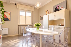 A modern kitchen with a white table, clear chairs, a vase of flowers, and a radiator. - Frontemura House with a Terrace (Lucca)