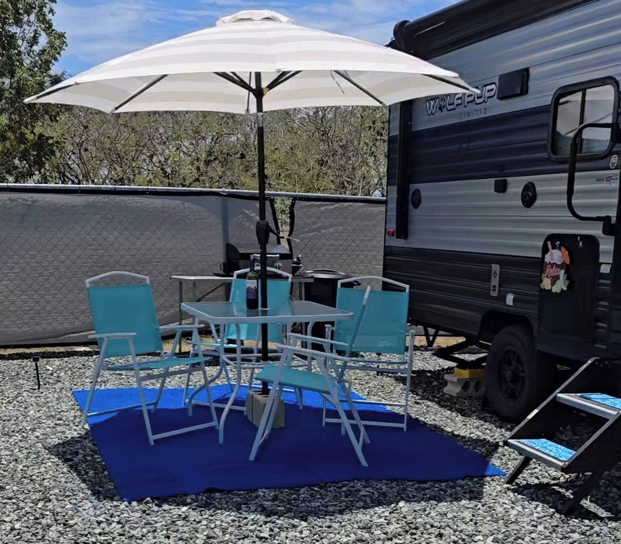 An RV with a covered outdoor seating area, including a table and chairs.