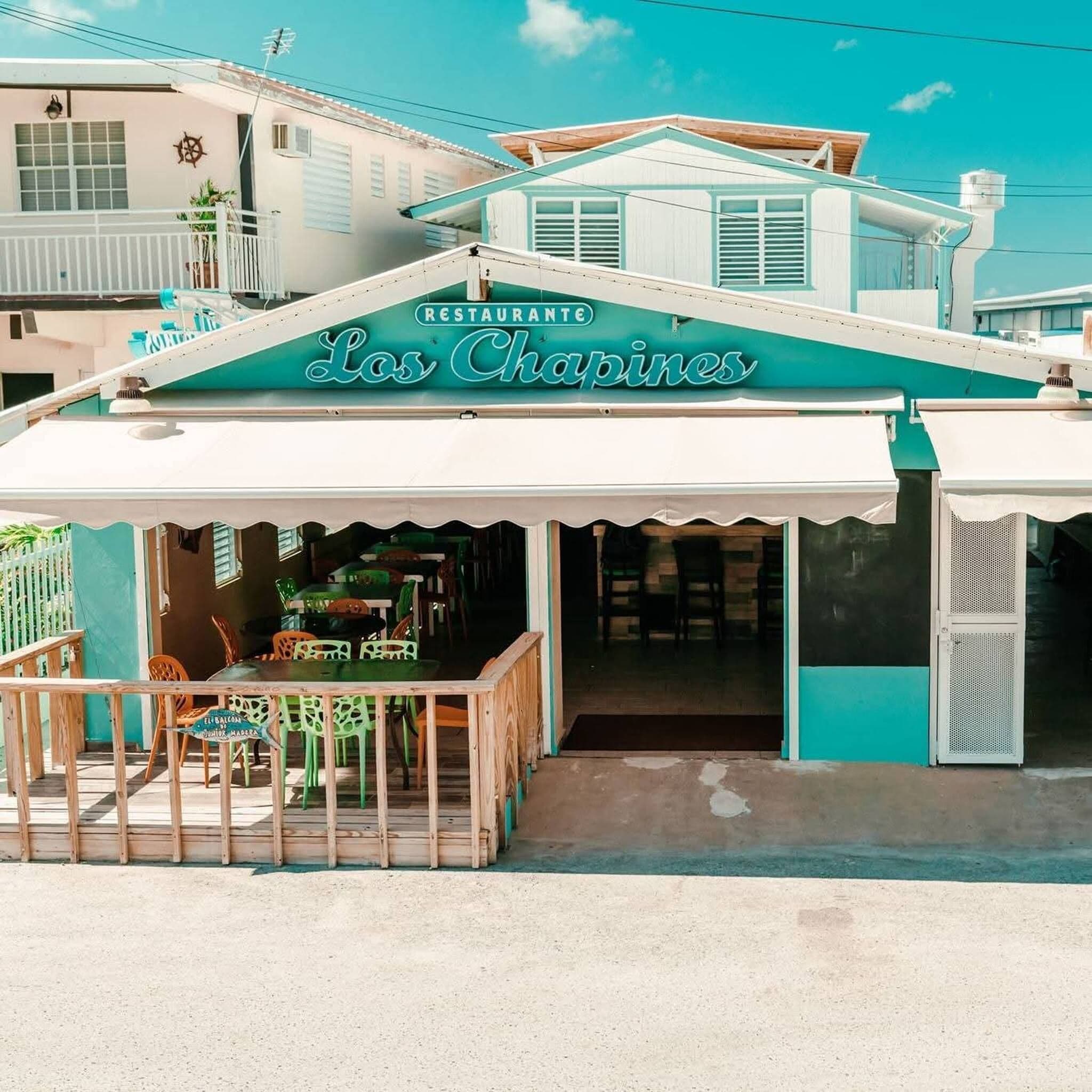 Un restaurante llamado 'Los Chapines' con un área de estar cubierta al aire libre y vistas al océano.