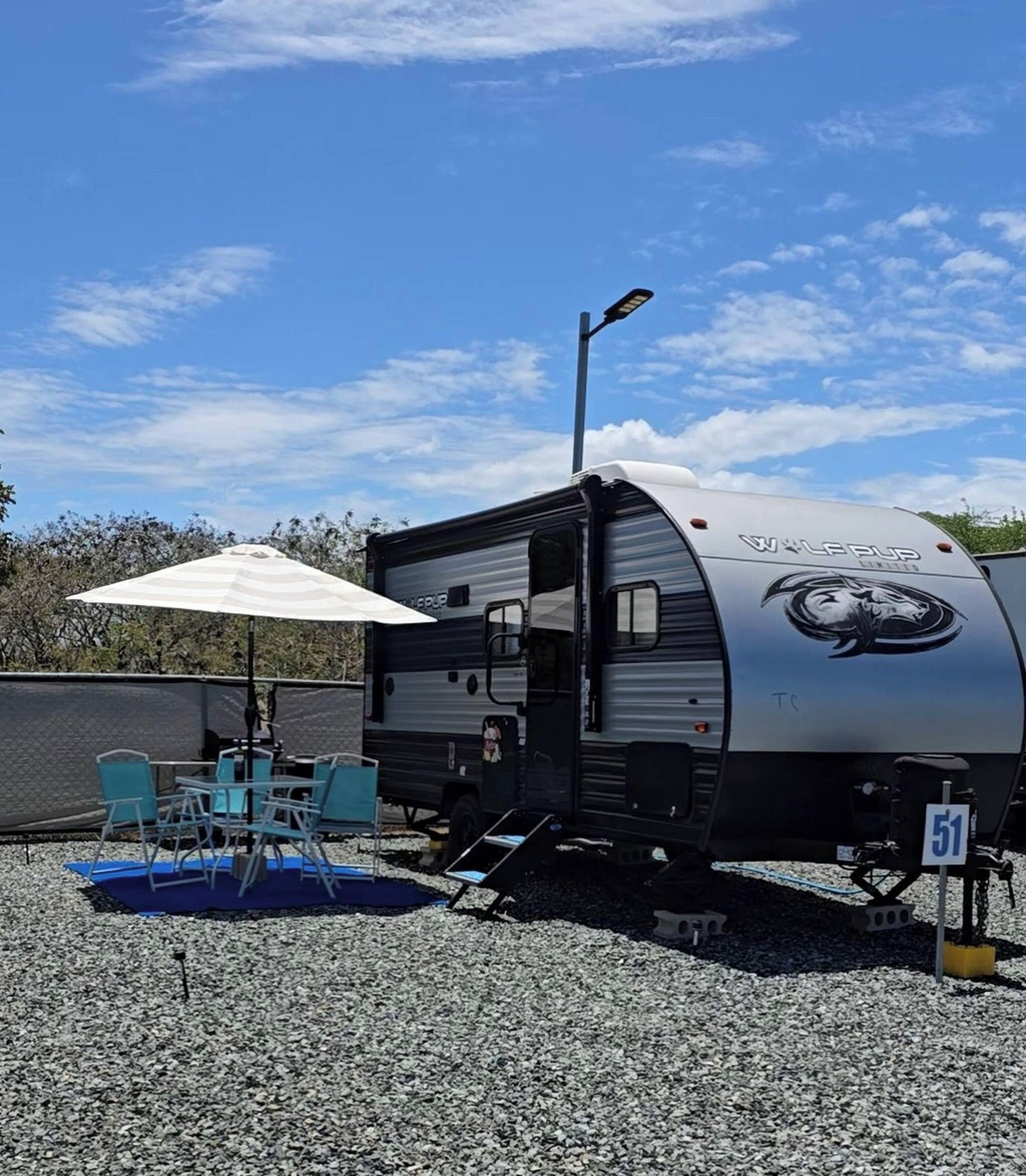 A mobile home with a covered patio area, outdoor seating, and a number sign.
