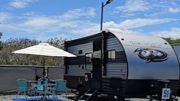 A mobile home with a covered patio area, outdoor seating, and a number sign.