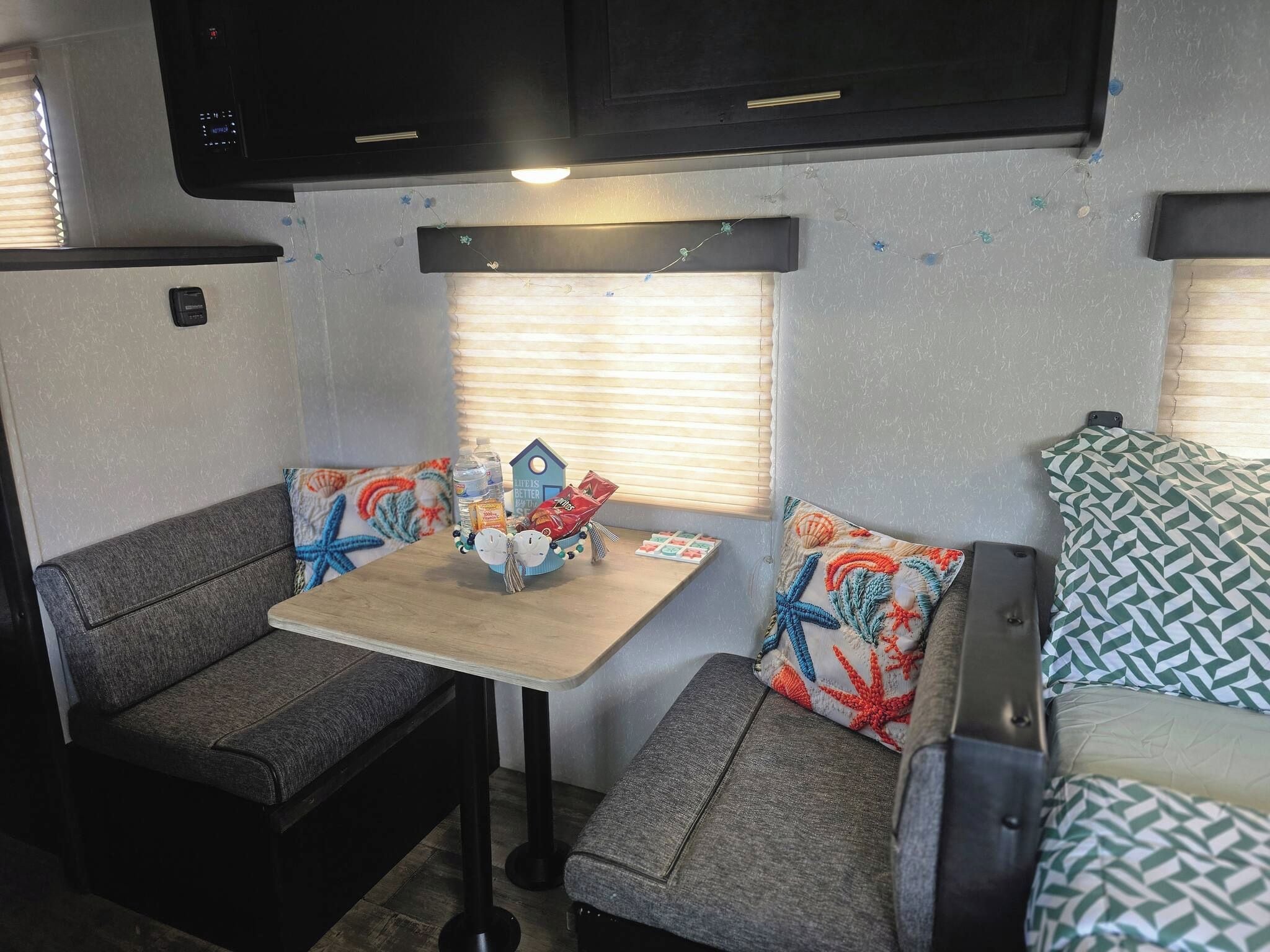 Interior compacto de autocaravana con kitchenette, zona de estar y una pequeña mesa.