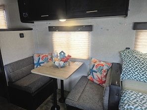 Interior compacto de autocaravana con kitchenette, zona de estar y una pequeña mesa.