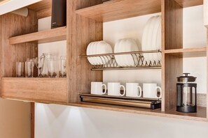 A wooden shelf unit with glassware, plates, and mugs. - w* | Dreamy & Cozy Loft in the Heart of Bogotá (Bogotá)