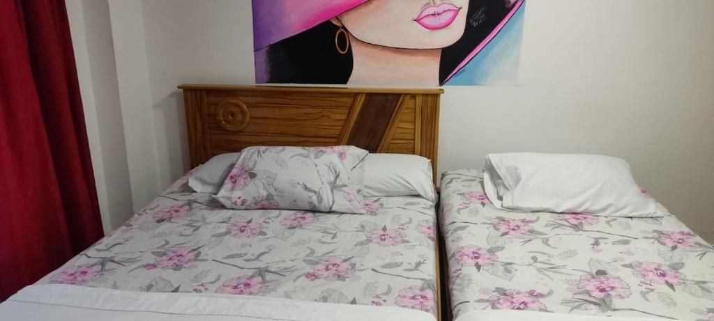 Una habitación con dos camas, cada una con ropa de cama floral y cabeceros de madera.