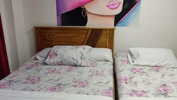 Una habitación con dos camas, cada una con ropa de cama floral y cabeceros de madera.