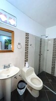 Un baño con lavamanos, inodoro y zona de ducha.