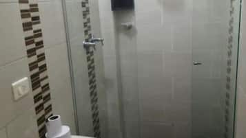 Une petite salle de bain fermée, équipée de toilettes, d’un lavabo et d’une douche.
