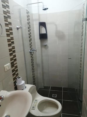 A small, enclosed bathroom with a toilet, sink, and shower.