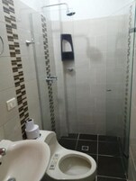 Un baño pequeño y cerrado con inodoro, lavabo y ducha.