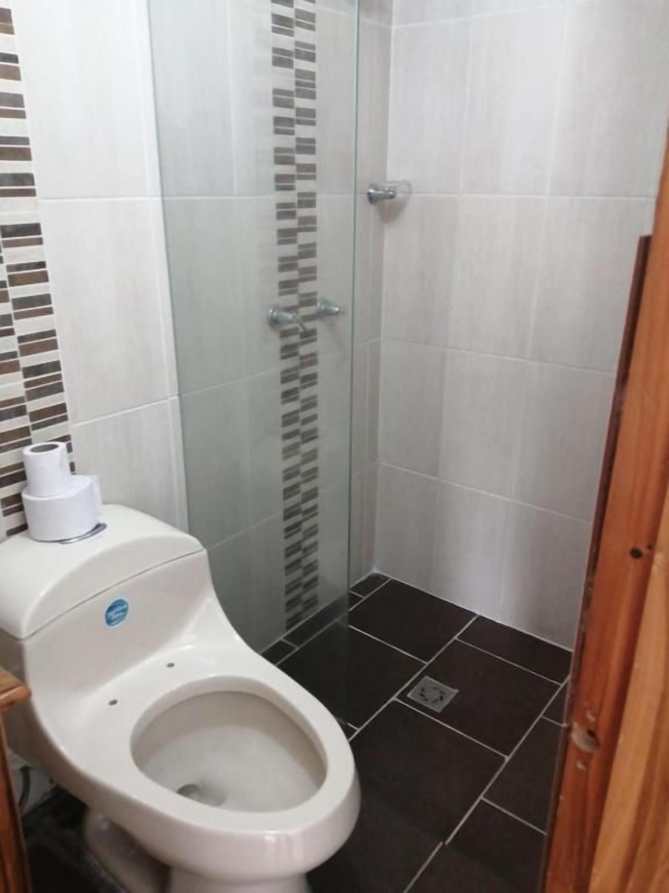 A bathroom with a toilet, a shower stall, and tiled walls.