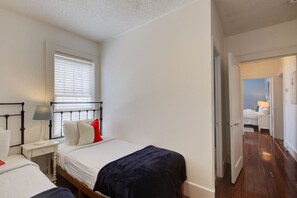 Ein Schlafzimmer mit einem Bett, Nachttisch, Lampe und einem Fenster mit Jalousien.