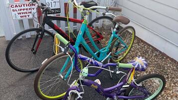 Three bicycles parked outside a house with a caution sign for slippery surfaces.