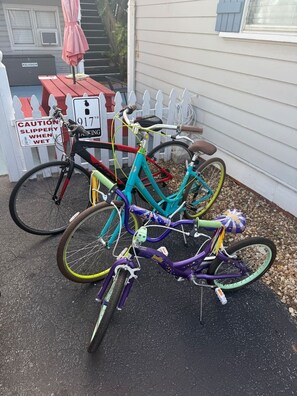 Drie fietsen staan buiten een huis, met een waarschuwingsbord voor gladde oppervlakken.