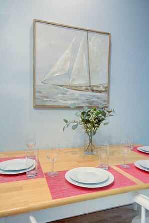 Una mesa de comedor dispuesta con platos, vasos y un florero con flores.